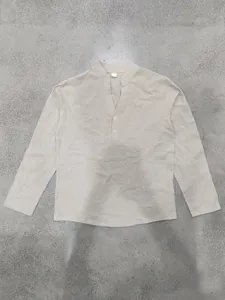 Flachgelegte Detailansicht der Textur eines beigen Leinen-Henley-Hemdes mit Stehkragen.