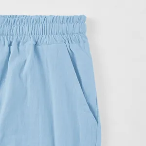 Close-up of light blue men's linen shorts showing elastic waistband and pocket detail