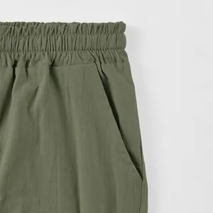 Close-up detail of olive green men's linen shorts with elastic waistband and pocket