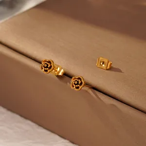 Primo piano di eleganti orecchini a lobo a fiore placcati in oro su un portagioie strutturato.