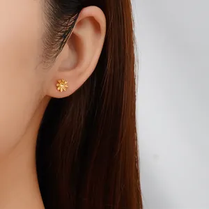 Dettaglio di un elegante orecchino a lobo a fiore dorato con design a margherita minimalista
