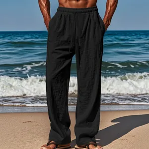 Detail view of men's loose black linen pants with drawstring waist at a sunny beach.