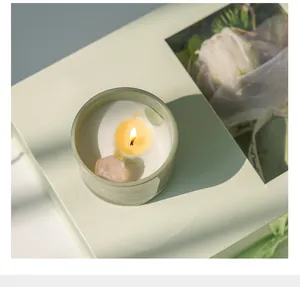 Vela aromática con piedras de cristal en caja verde, detalle de decoración relajante para el hogar.