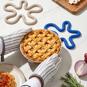 Flower-shaped silicone heat insulation mats on a marble kitchen counter with a baked pie