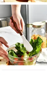 Professional white silicone spatula with wooden handle mixing a fresh green salad