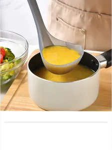 Close-up of a gray silicone ladle scooping yellow porridge from a white non-stick pot