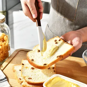 Silicone cream spatula with ergonomic wood handle spreading fresh butter on toast