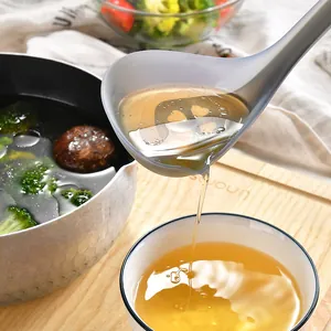 Gray silicone oil filtering soup ladle pouring broth into a bowl in a kitchen