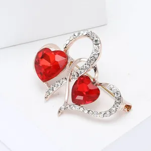 Primer plano de un elegante broche de doble corazón con cristales rojos facetados