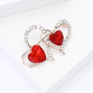Vista detallada de un broche de doble corazón con cristales rojos y diamantes de imitación