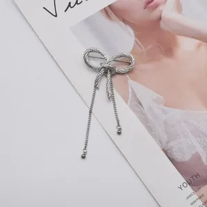 Close-up macro view of a silver metallic bow knot brooch featuring elegant hanging tassels