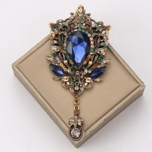 Close-up detail of a vintage palace style brooch with blue teardrop crystal and colorful rhinestones