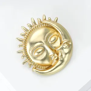 Makroansicht einer matten goldenen Sonnen- und Mondbrosche mit Vintage-Gesichtsdetails