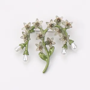 Detailed view of a vintage floral brooch with green stems and elegant hanging pearls