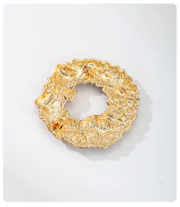 Detailed back view of a textured gold Christmas wreath brooch showing the secure pin fastener