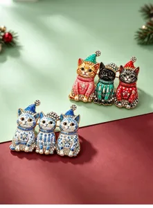Nahaufnahme festlicher Katzenbroschen in Weihnachtsfarben und blau-weißen Porzellanmotiven.