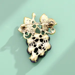 Détail du fermoir doré d'une broche raisin vintage avec de jolies perles violettes.