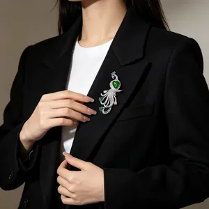 Eleganter Pfau-Brosche mit einem grünen Herzstein an einem schwarzen Blazer für Damen