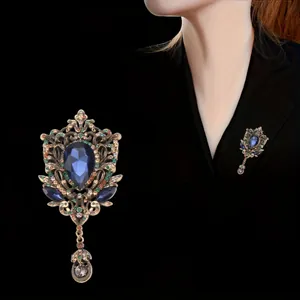 Vintage palace style hollow brooch with blue faceted gem and elegant tassel detail
