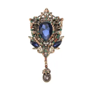 Vintage court style brooch with large blue pear-shaped rhinestone and hollow gold-tone filigree