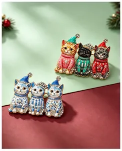 Nahaufnahme von Weihnachts-Katzenbroschen mit bunten Pullovern und Porzellanmustern.