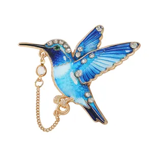 Elegante blauwe gradiënt emaille kolibrie broche met strass steentjes en gouden ketting.