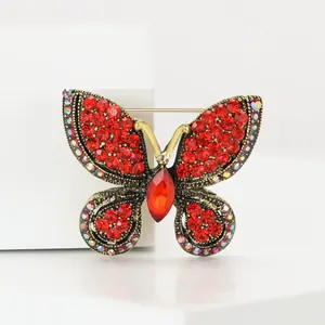 Gros plan détaillé d'une broche papillon vintage avec des strass rouges et un alliage doré