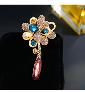 Detail shot of an elegant gold floral brooch with blue and purple water drop crystals.