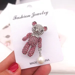 Detaillierte Nahaufnahme einer rosa Strass-Bärenbrosche mit weißer Perle auf Karte