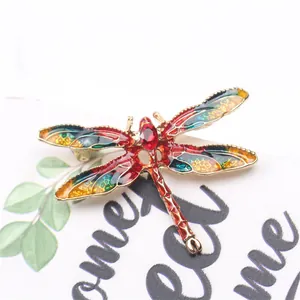 Close-up of vintage enamel dragonfly brooch with red rhinestones and colorful wings