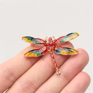 Close-up detail of a vintage dragonfly brooch with colorful enamel and red crystal