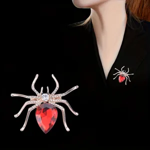Macro detail of a gold-tone spider brooch with a red gemstone and sparkling rhinestones
