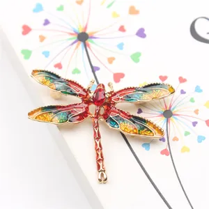 Detail shot of a vintage dragonfly brooch with colorful enamel and red crystal inlay