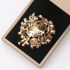 Detailed close-up of gold-colored crystal brooch back with pin clasp in a gift box