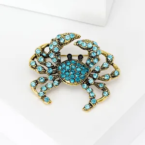 Vintage Goldkrabbe Brosche mit hellblauen Strasssteinen auf weißem Hintergrund fläche