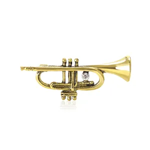 Antique gold-plated trumpet brooch with sparkling crystal for elegant suit lapels.