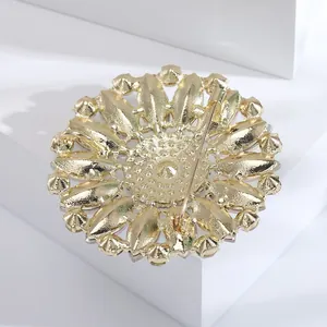 Detail view of the back of a vintage flower brooch with a gold-tone pin fastener.