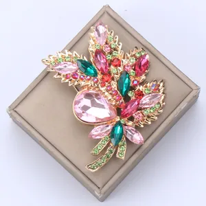 Close-up of elegant floral bouquet brooch with pink and green crystals on a gold base.