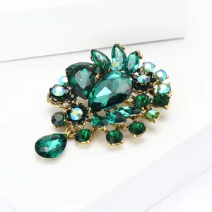 Detaillierte Makroaufnahme einer grünen Strass-Blumenbrosche auf einem weißen Sockel