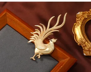 Close-up of golden rooster brooch with matte finish and detailed feather texture