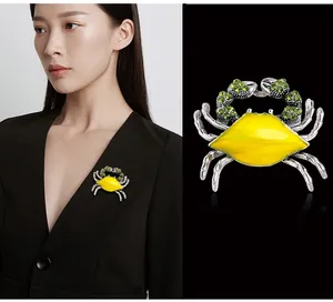 Detailed view of a stylish alloy crab brooch with yellow enamel and green rhinestones