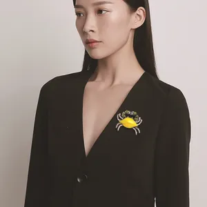Artistic yellow enamel crab brooch with green rhinestones worn on a elegant black blazer