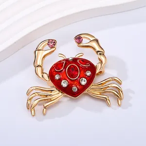 Elegant gold-tone crab brooch featuring vibrant red enamel and sparkling pink rhinestones