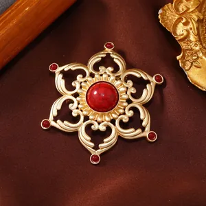 Vintage gold-finished openwork lotus brooch with central red faux turquoise stone.