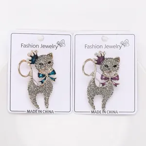 Vista dettagliata di due spille di gatto con strass di lusso con corone e fiocchi colorati