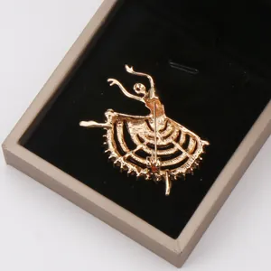 Detail view showing the back side of a gold-toned ballet dancer brooch in a box