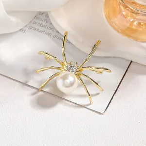 Close-up of a vintage gold spider brooch with large pearl and sparkling rhinestones
