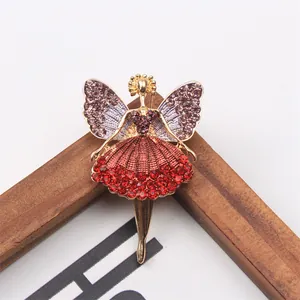 Detailed close-up of a golden ballet girl angel brooch with red rhinestones on a frame
