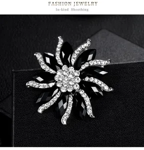 Detail view of a black flower alloy brooch with sparkling rhinestones on black background