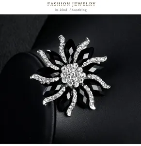 Detailed close-up of elegant black and white rhinestone flower brooch on leather background
